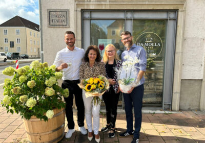Vier Menschen stehen vor neuem Café Da Molla mit Blumen und Kaffee in der Hand